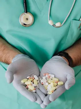 Mass-Tort-Cases Medical professional with stethoscope displaying assorted pharmaceutical pills and medicines in sterile gloved hands represents mass tort cases