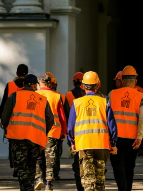Workers-Compensation Construction workers in safety vests and hard hats walking on job site wearing high-visibility PPE gear represents workers compensation claims